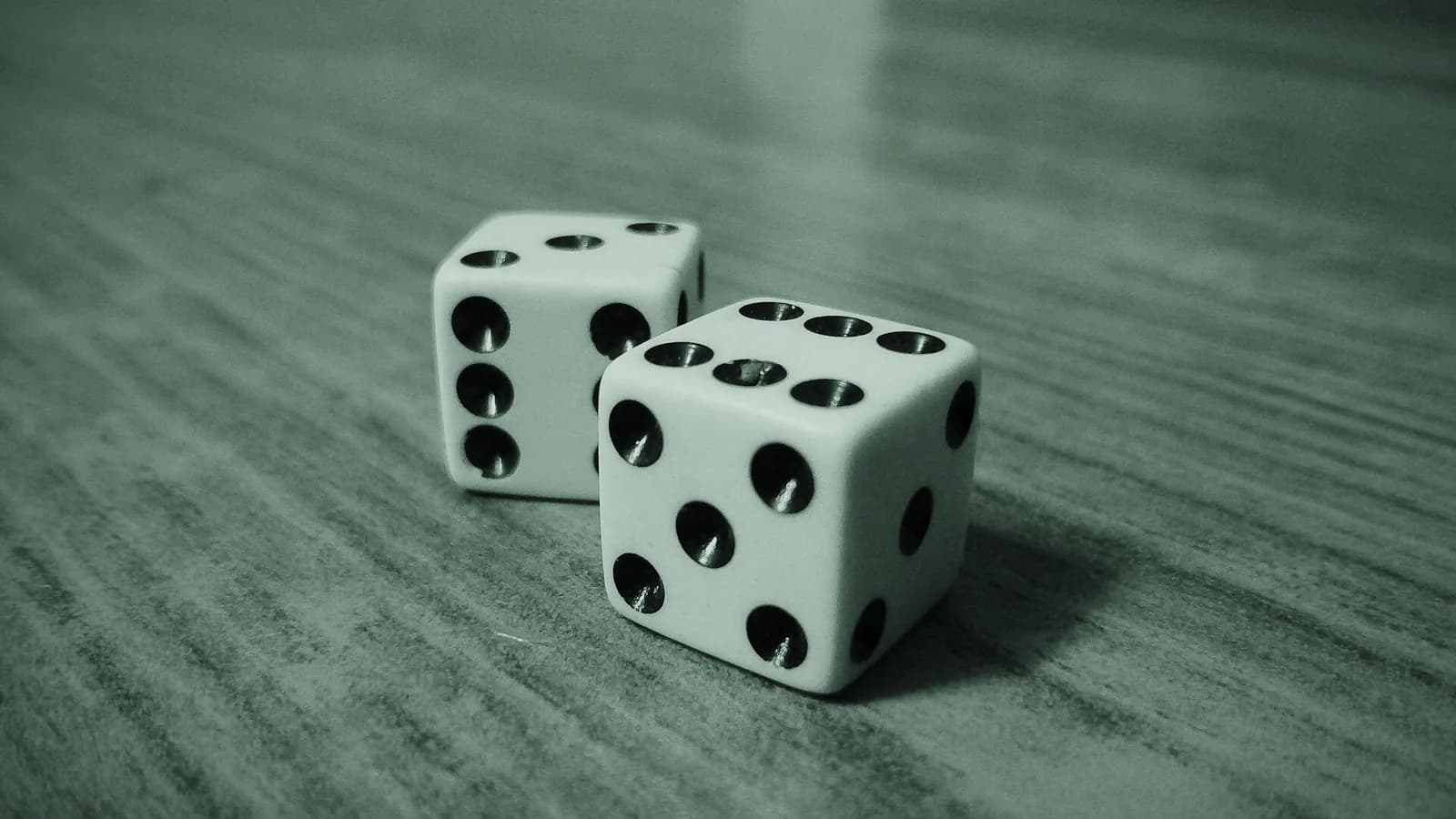 Two physical dice resting on a wooden table.