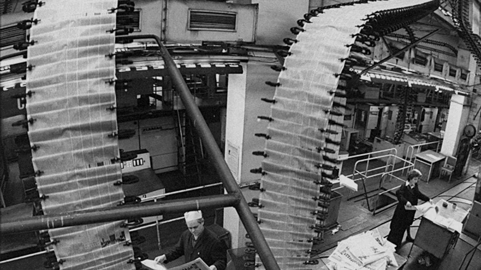 An archival newspaper printing operation with paper moving through a press.